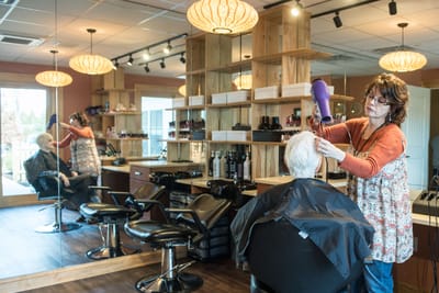 A woman styling a resident's hair in the salon