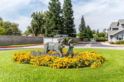 Statue of a child with a dog surrounded by flowers