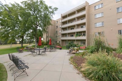 Outdoor seating area with gardens and building in background