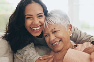 Two women smiling and embracing indoors