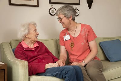 Caregiver interacting with a senior resident on a couch