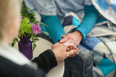 Two hands holding together with flowers on a table