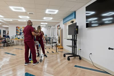 Staff assisting a resident in a therapy area