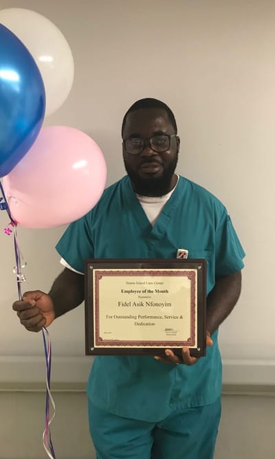 Employee of the Month holding a certificate and balloons