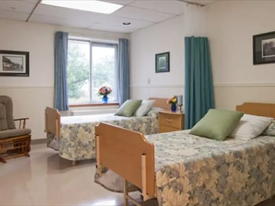 Two beds in a well-lit resident room with floral bedding