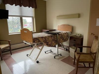 Private resident room with an adjustable bed and chairs