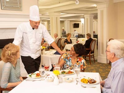 Dining room scene with residents and staff interacting