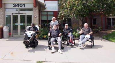 Residents in wheelchairs at the facility entrance