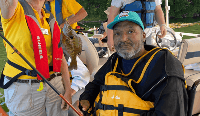 Resident fishing on a boat with staff assistance