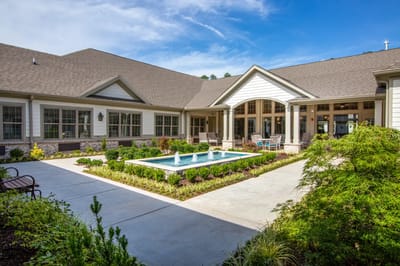 Exterior view of a senior living facility with a garden and fountain