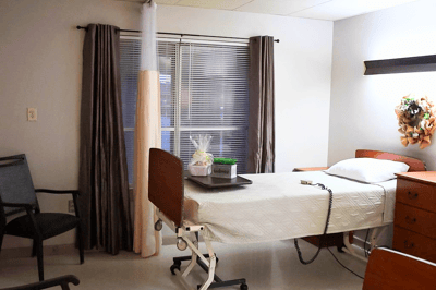 Interior view of a patient room with a bed and chair