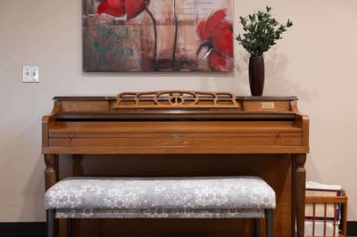 A piano with a bench and wall art in a lobby area