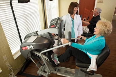 Residents engaging in physical therapy with staff assistance