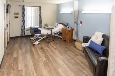 A well-furnished resident room with bed and seating area