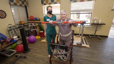 A staff member assisting a resident with therapy equipment