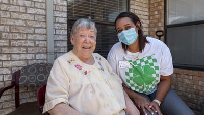 Resident and staff member smiling outside