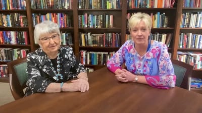 Two women chatting in a library-like interior space