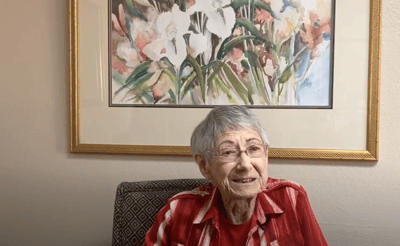 Resident smiling in an interior setting with floral artwork