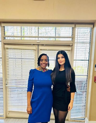 Two women posing in a common area of a facility.