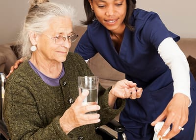 Caregiver assisting a senior with a glass of water.
