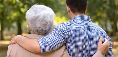 An older woman and a young man enjoying a walk outdoors.