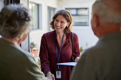 Staff member greeting two elderly residents.