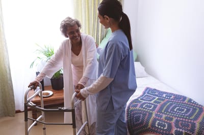 Caregiver assisting a resident with a walker.