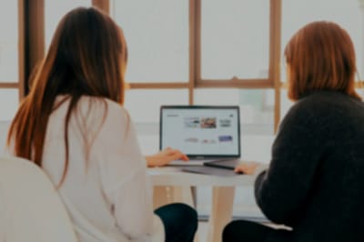Two women working on a laptop at a table.
