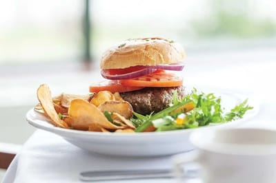 A gourmet burger with chips and salad on a plate.