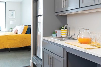 Bright kitchen area with orange drink and bed