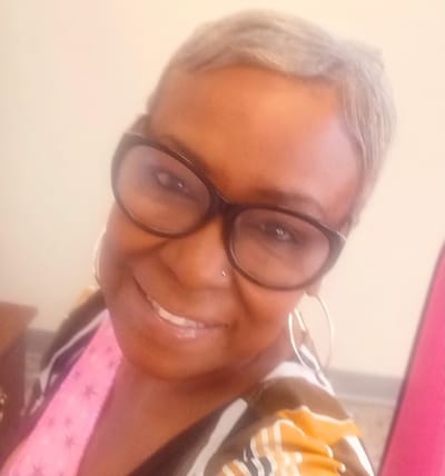 A smiling resident with short hair and glasses.