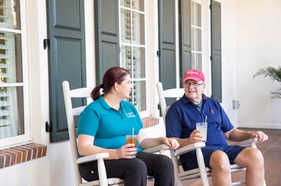 A staff member and resident enjoying drinks outdoors.
