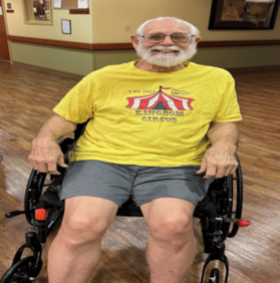 A smiling resident in a wheelchair wearing a colorful shirt.