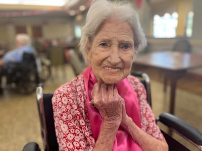 Elderly resident smiling in a communal area.