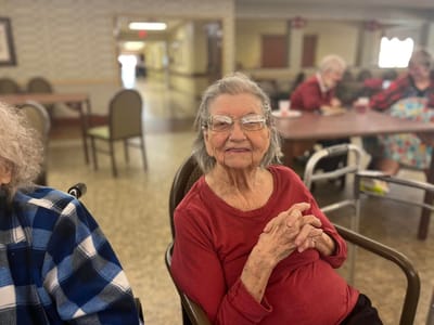 Elderly woman smiling in a common area.