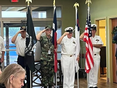 Veterans saluting during a ceremony indoors