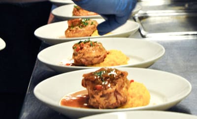 Plated meals with garnishes being prepared.