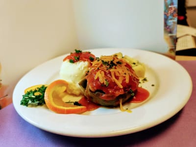 A plate of meatloaf with mashed potatoes and garnish.