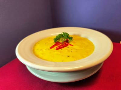 Bowl of soup garnished with parsley and red pepper