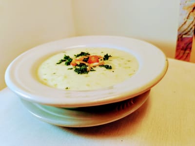 Bowl of creamy soup garnished with herbs.