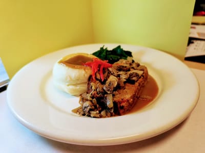 Plate of meatloaf with sides served in dining area.