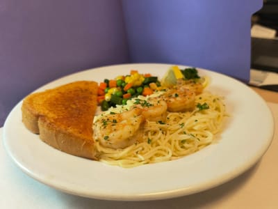 A plate of shrimp scampi with vegetables and toast.