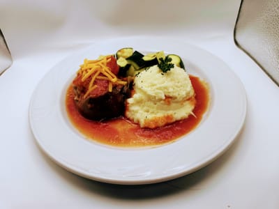 Plate of food with meatloaf, mashed potatoes, and vegetables.