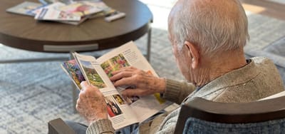 Senior man reading a magazine in a cozy setting.