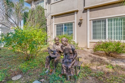 Statue of a couple sitting on a bench in a garden.