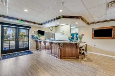 Reception area with a wooden desk and plants.
