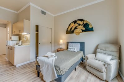 A cozy private resident room with a bed and seating.