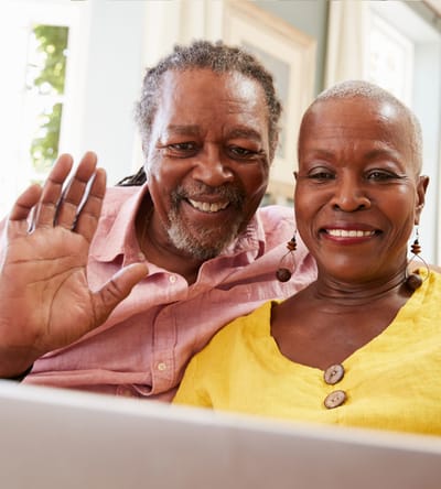 Two residents smiling and waving at a video call