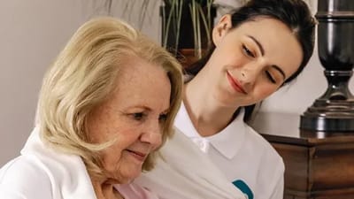 Caregiver assisting resident in a warm interior setting