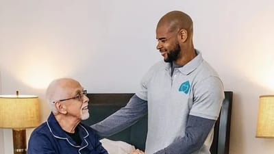 Caregiver smiling with a resident in a bedroom
